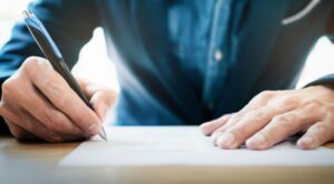 Close up businessman signing contract making a deal. TLS Wills and Estates